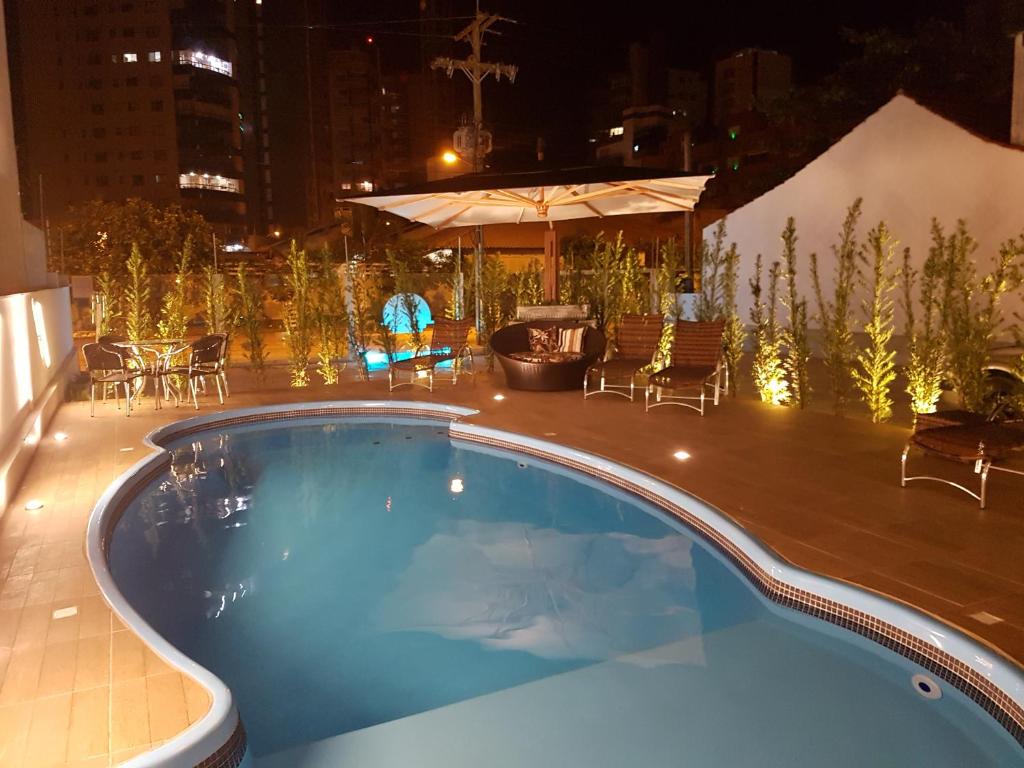 uma piscina à noite com mesa e cadeiras em Casa de Oliveira Pousada em Torres