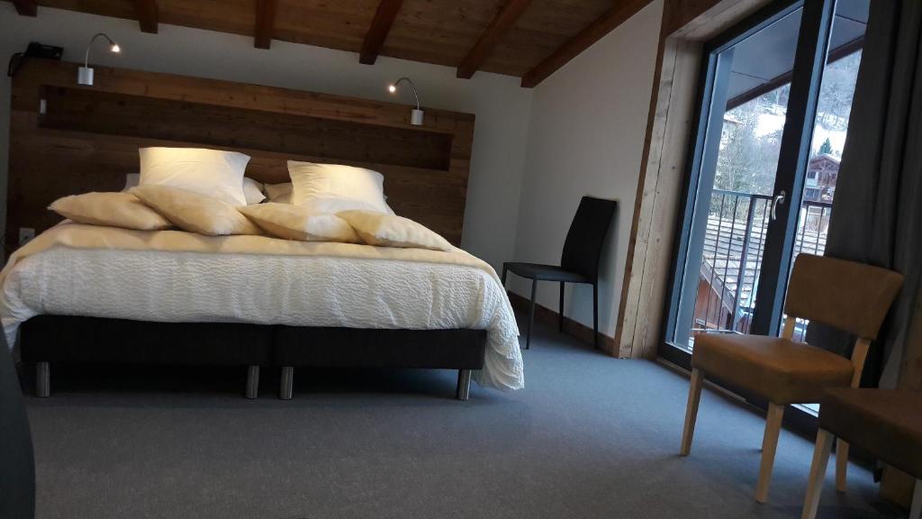 a bedroom with a bed and a large window at Hotel L'alpin in Landry