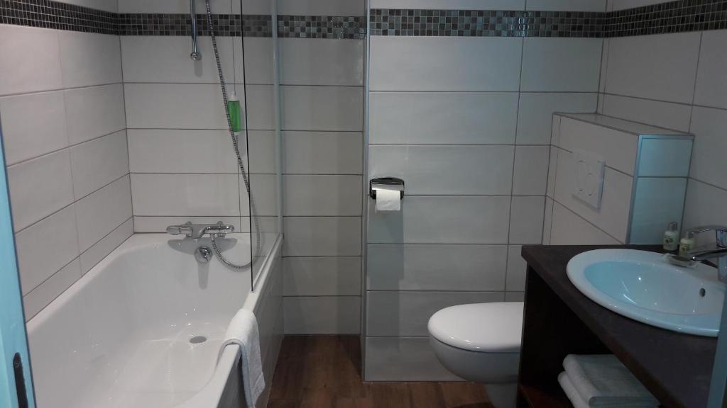 a bathroom with a tub and a toilet and a sink at Hotel L'alpin in Landry