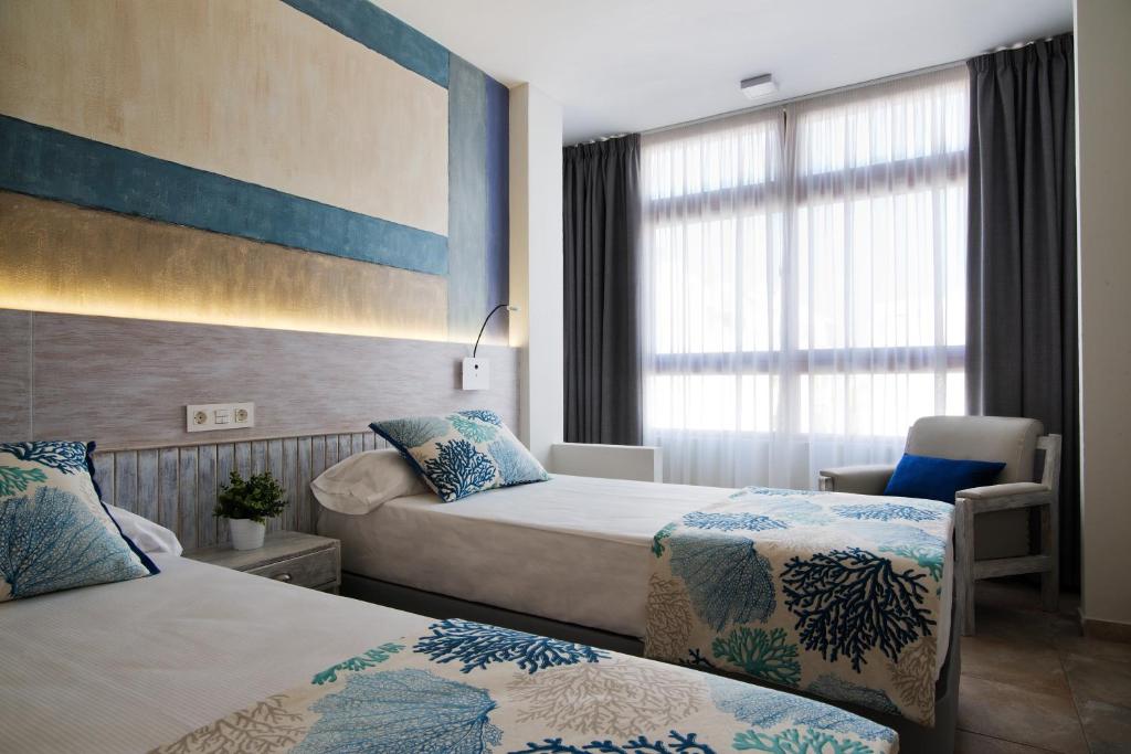 ラスパルマス・デ・グランカナリアにあるApartHotel Idafeのベッド2台と窓が備わるホテルルームです。