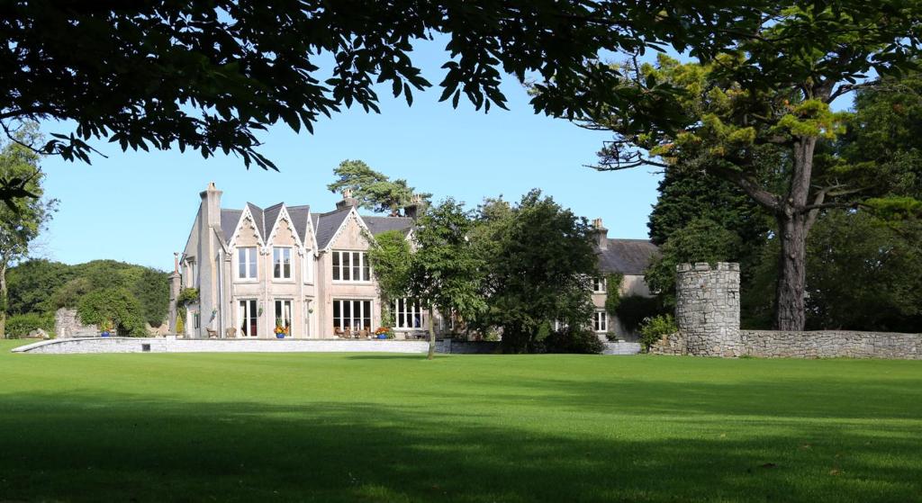 uma casa grande com um relvado verde em frente em Parc-Le-Breos House em Penclawdd