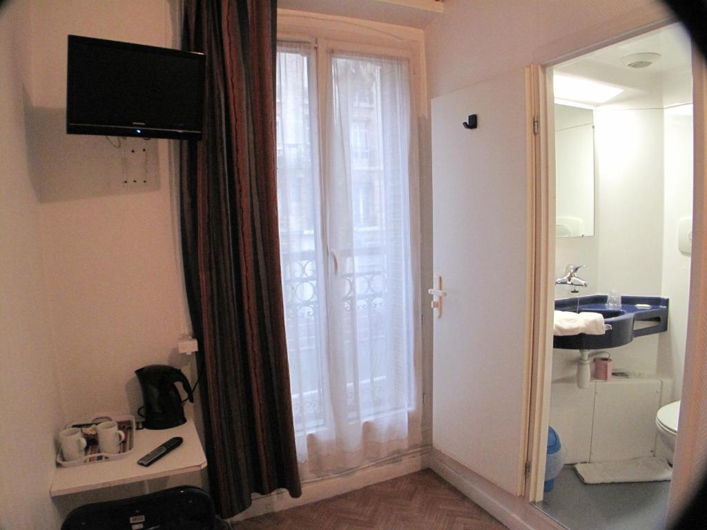 Habitación de hotel con baño y ventana grande. en Hotel Feria (FR) en Clichy