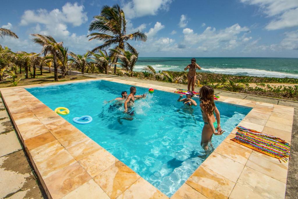a group of people playing in a swimming pool next to the beach at Pousada Cabanas de Búzios in Nísia Floresta
