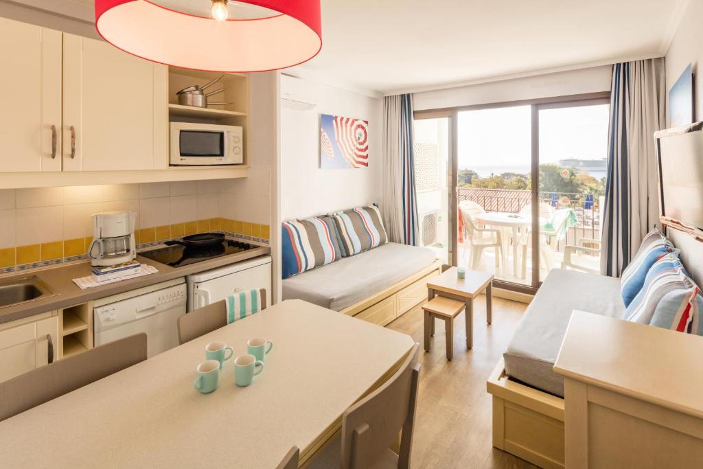 a small kitchen and a living room with a table at Résidence Pierre & Vacances l'Ange Gardien in Villefranche-sur-Mer