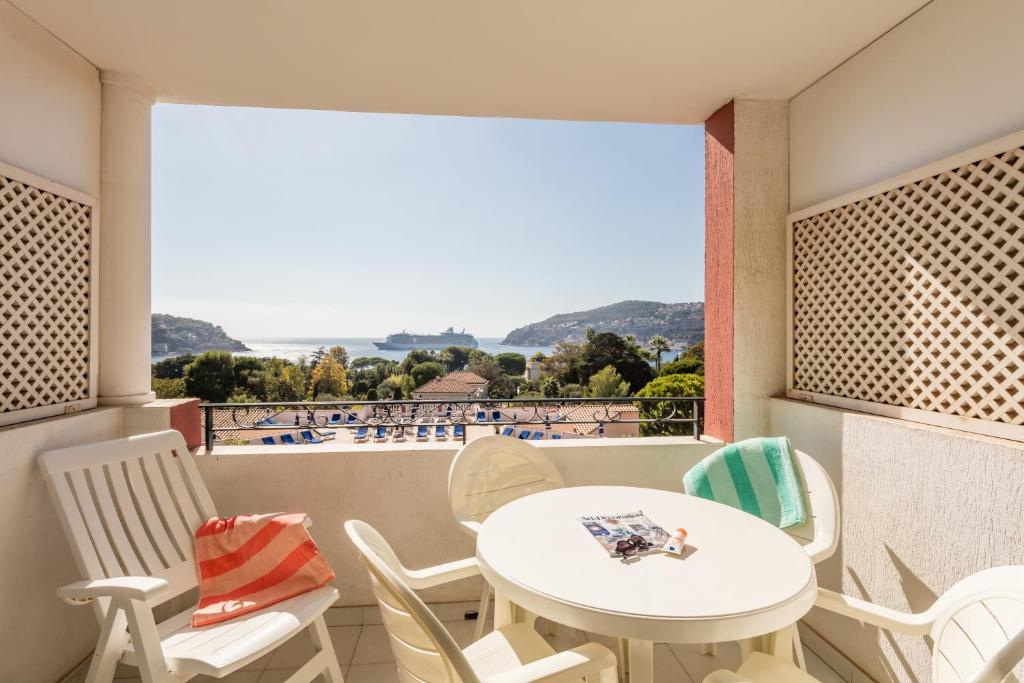 a room with a table and chairs and a large window at Résidence Pierre & Vacances l'Ange Gardien in Villefranche-sur-Mer