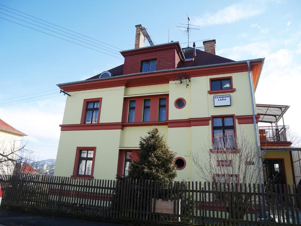 una gran casa blanca con una valla delante en Pension Lada en Karlovy Vary