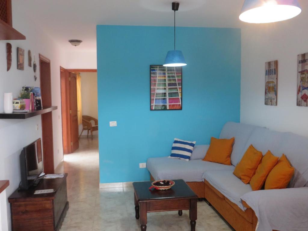 a living room with a couch and a blue wall at Coqueto apartamento in Famara