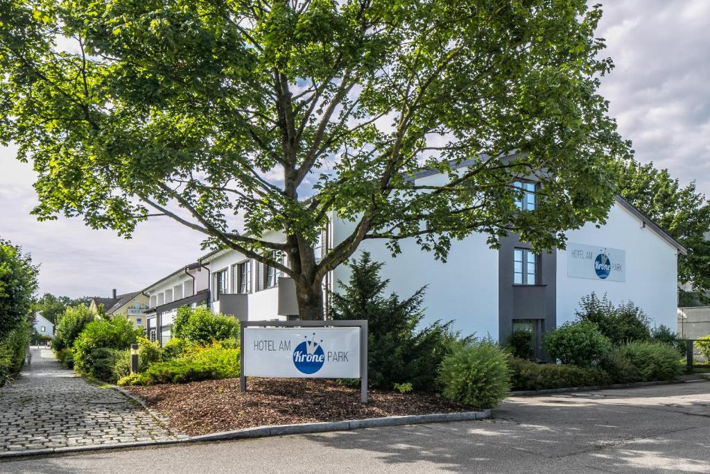 a sign in front of a tree in front of a building at Hotel am Krone Park in Olching