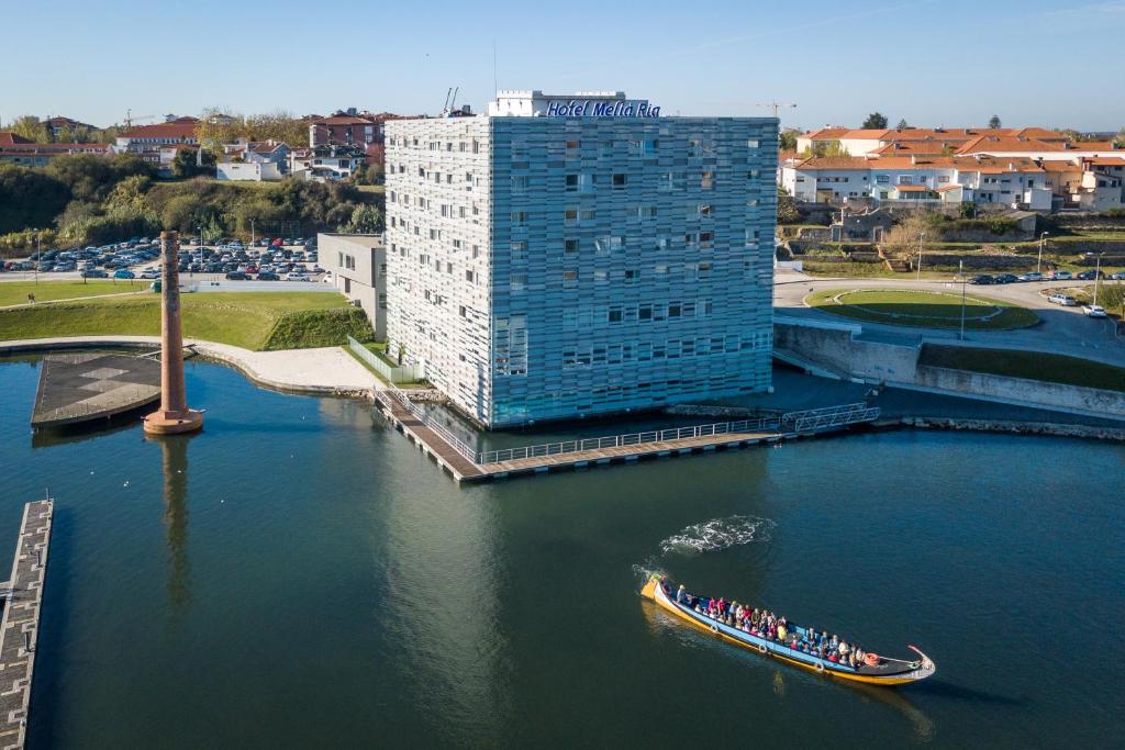 a boat in the water next to a tall building at Melia Ria Hotel & Spa in Aveiro