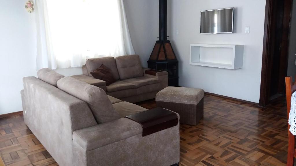 ein Wohnzimmer mit einem Sofa und einem Stuhl in der Unterkunft Casa da Vó Nelsi in Gramado