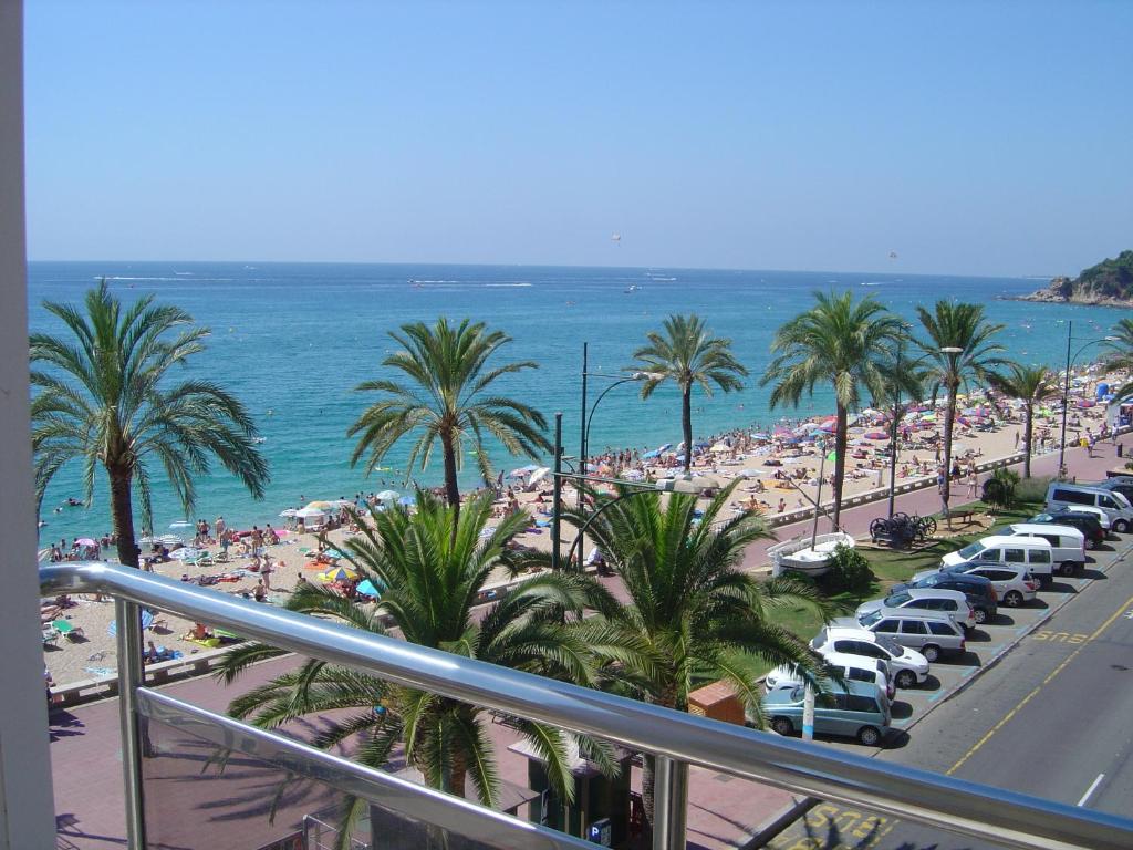 a view of a beach with palm trees and cars at Apartaments Tropic in Lloret de Mar