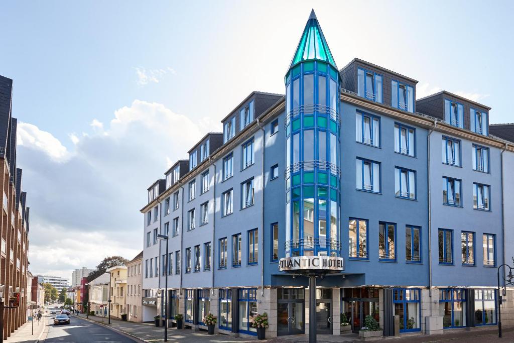 ein blaues Gebäude mit einem Turm auf einer Straße in der Unterkunft Atlantic Hotel Vegesack in Bremen-Vegesack