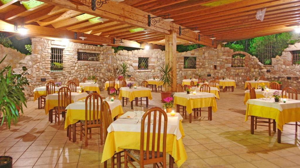 a restaurant with yellow tables and chairs and a stone wall at Hotel La Pergola in Moniga