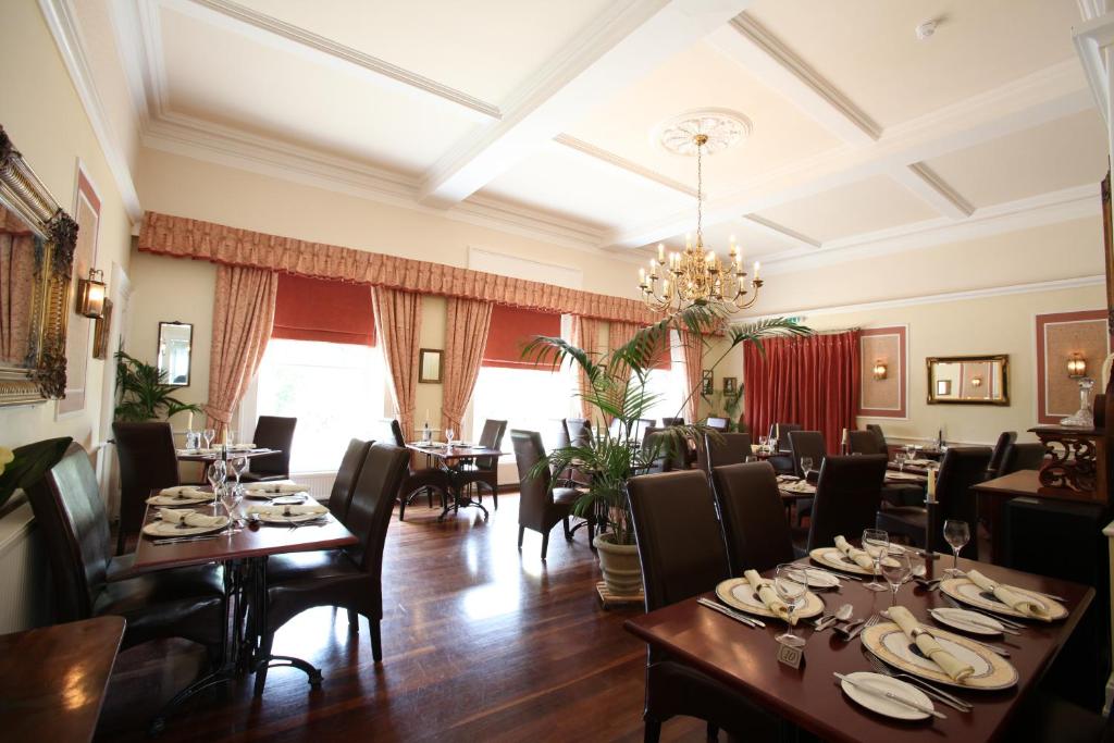 a dining room with tables and chairs and a chandelier at Fernhill Hotel in Lyme Regis