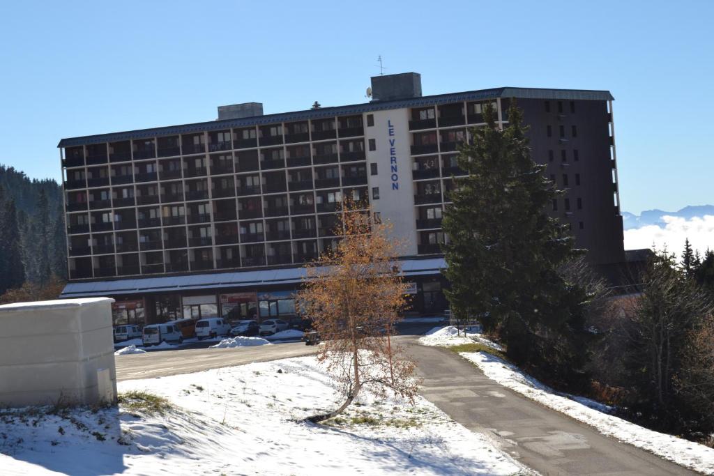 un edificio con un árbol delante de él en Appartement Le Vernon en Chamrousse