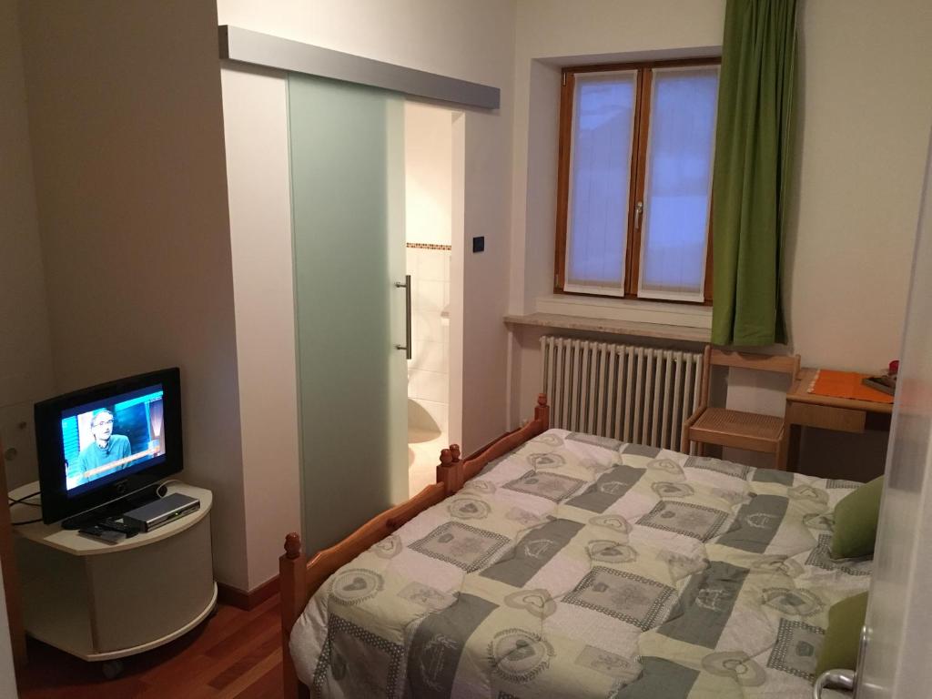 a small bedroom with a bed and a television at Affittacamere Penasa in Rabbi