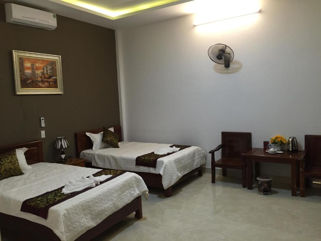 a room with two beds and a table and a desk at Hoa Lu Hotel in Bản Giỏ (1)