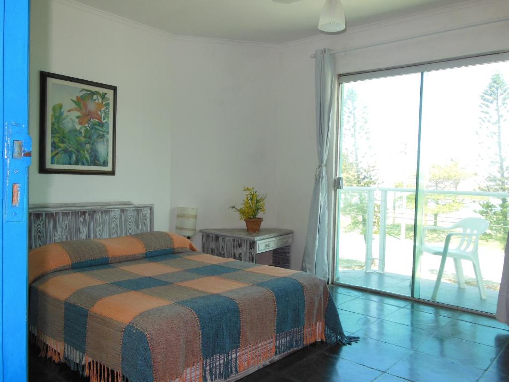 a bedroom with a bed and a sliding glass door at Praia Sul Studios in Peruíbe