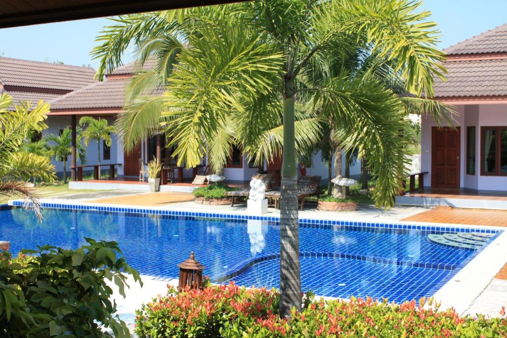 una palmera frente a una piscina en Waterside Resort, en Pran Buri