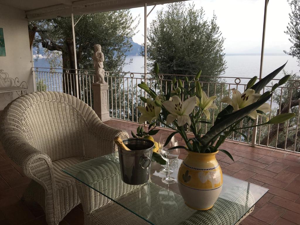 a glass table with a vase of flowers on a balcony at Villa Petit Ludovica in Ravello