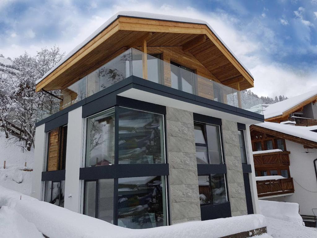 ein Haus im Schnee mit einem Holzdach in der Unterkunft Allegra in Samnaun