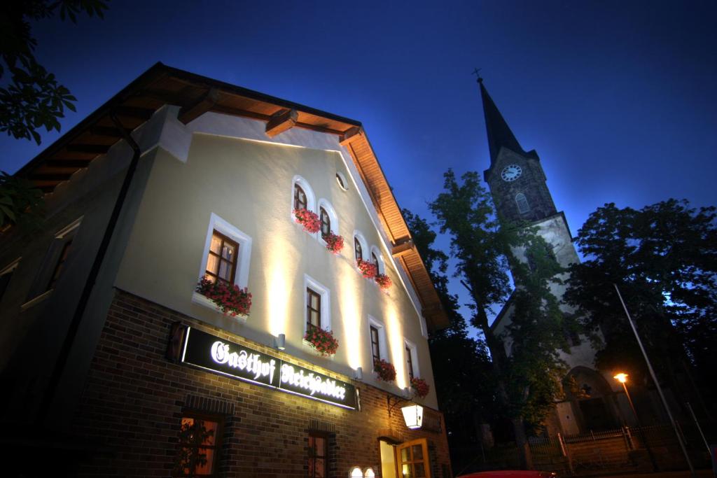 un edificio iluminado con una torre de reloj en el fondo en Landgasthof Reichsadler, en Höchstädt bei Thiersheim