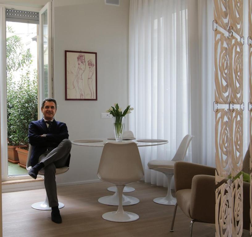 Milano Porta Venezia Suite Centro في ميلانو: رجل يجلس على كرسي بجانب طاولة