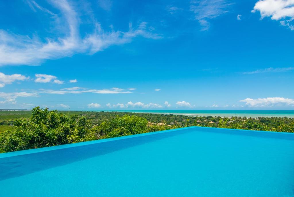 a swimming pool with a view of the ocean at Manacá Pousada Parque in Arraial d'Ajuda
