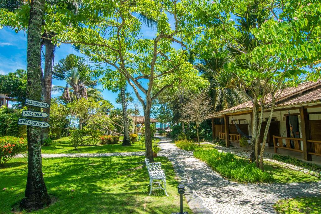 a garden with a bench in front of a building at Manacá Pousada Parque in Arraial d'Ajuda
