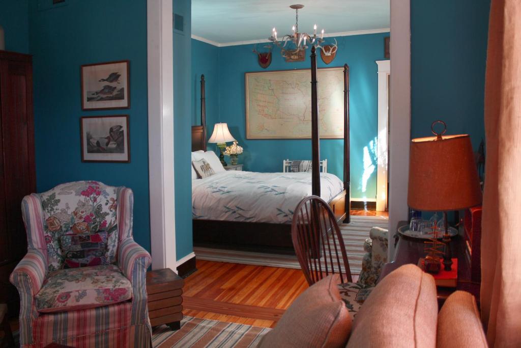 1 dormitorio con paredes azules, 1 cama y 1 silla en Inn at Court Square, en Charlottesville