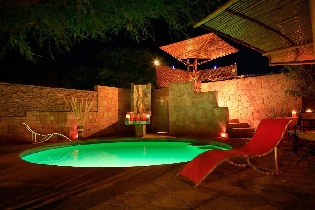 una pequeña piscina por la noche con una silla roja en Hotel Kimal, en San Pedro de Atacama