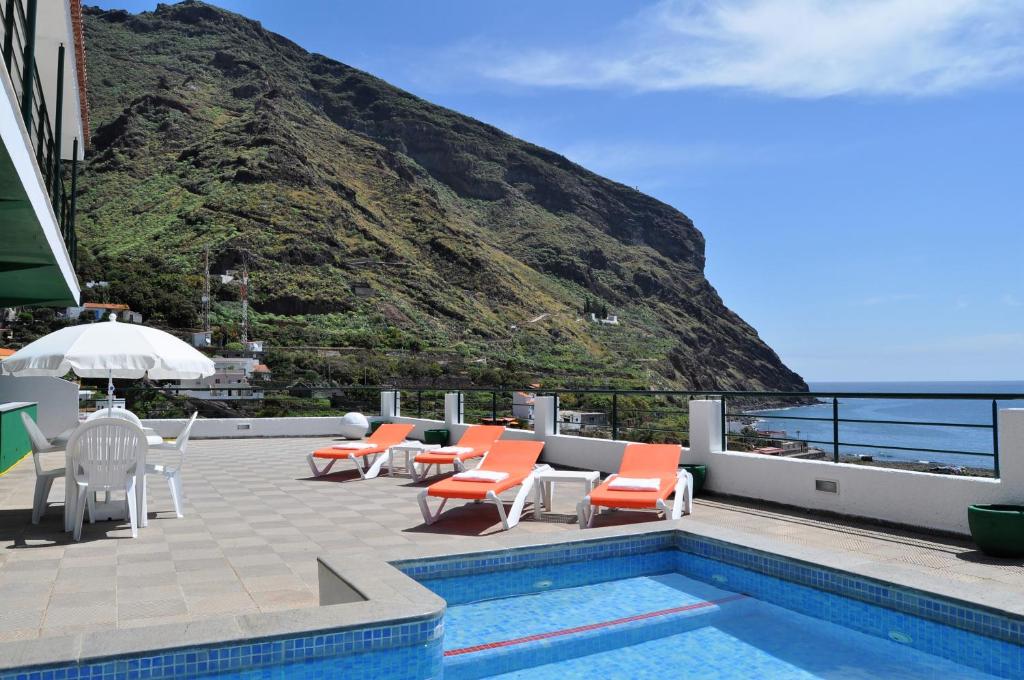 a pool with chairs and tables and a mountain at Villa GUACIMARA in Igueste