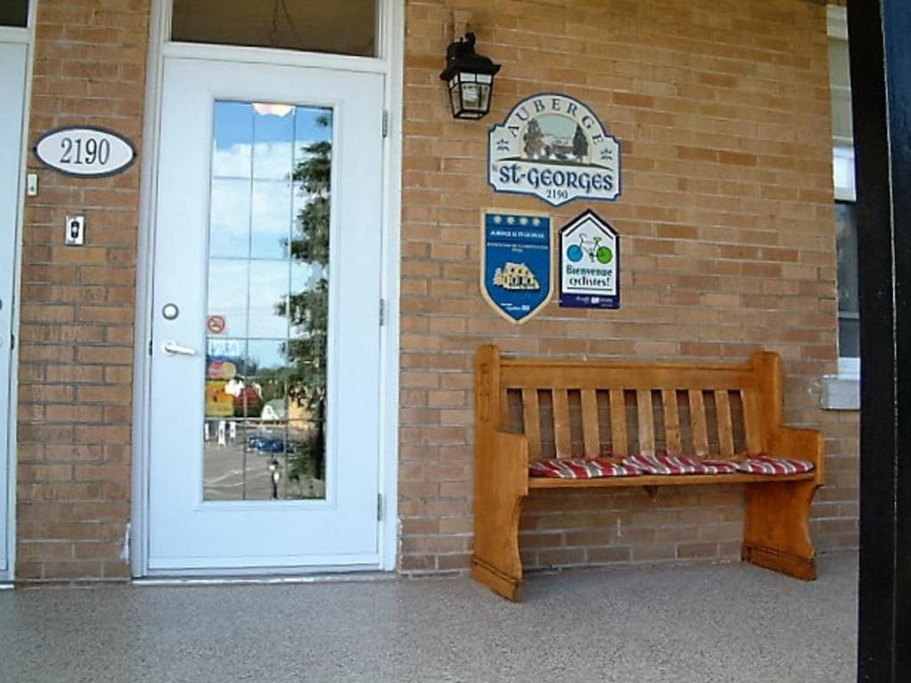 a wooden bench sitting in front of a brick building at Auberge le St-Georges in Saguenay