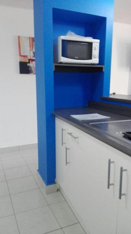 a kitchen with a microwave on a blue wall at Condominios La Ronda in Tegucigalpa