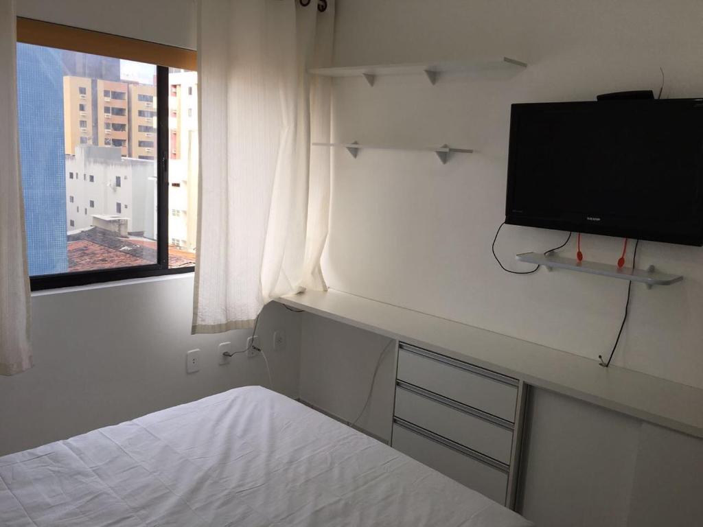 um quarto com uma cama e uma televisão de ecrã plano em Apartamento Jatiuca em Maceió