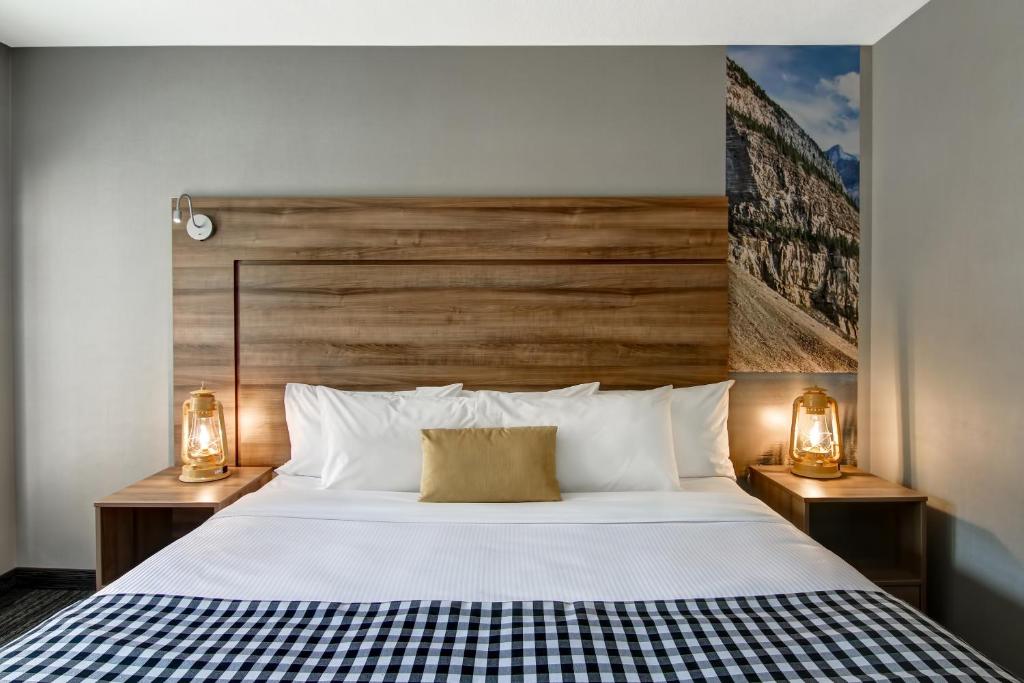 a bedroom with a large white bed with two lamps at Canalta Lodge in Banff