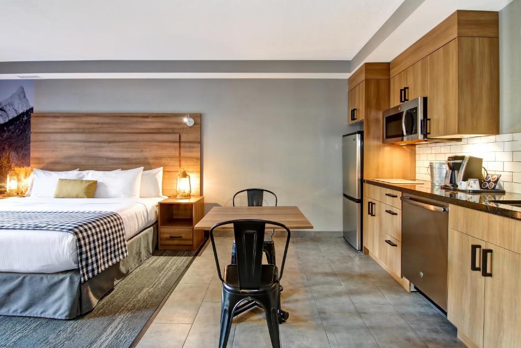 a hotel room with a bed and a table and a kitchen at Canalta Lodge in Banff
