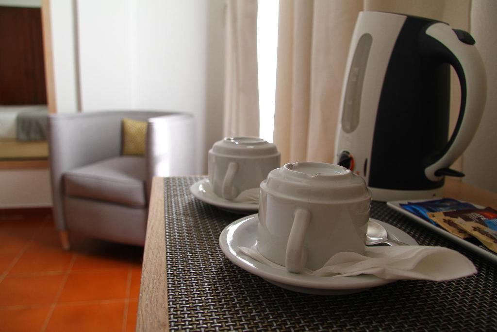 two cups on a table with a coffee maker at Best Western Hotel Dom Bernardo in Faro