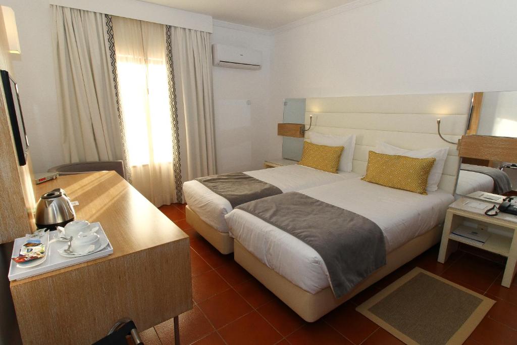 a hotel room with a large bed and a table at Best Western Hotel Dom Bernardo in Faro