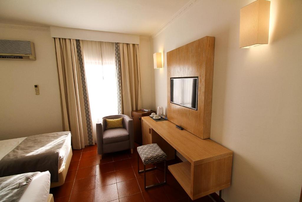 a hotel room with a desk and a bedroom at Best Western Hotel Dom Bernardo in Faro