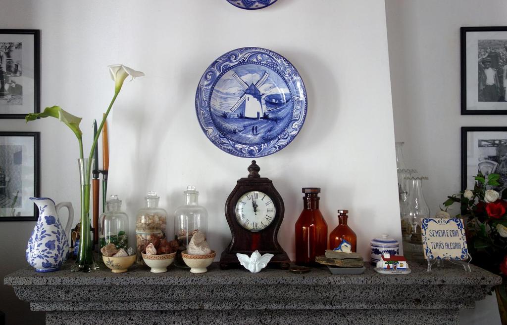 uma lareira com um relógio e outros itens sobre ela em Casa Tradicional da Vila em Vila Franca do Campo