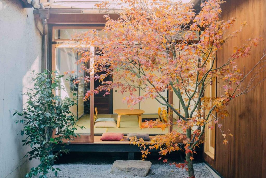 a tree with pink flowers in a room with a chair at Casa OGUMO in Kyoto