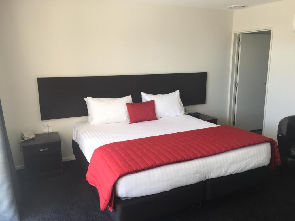 um quarto com uma cama grande e um cobertor vermelho em Rolleston Highway Motel em Rolleston