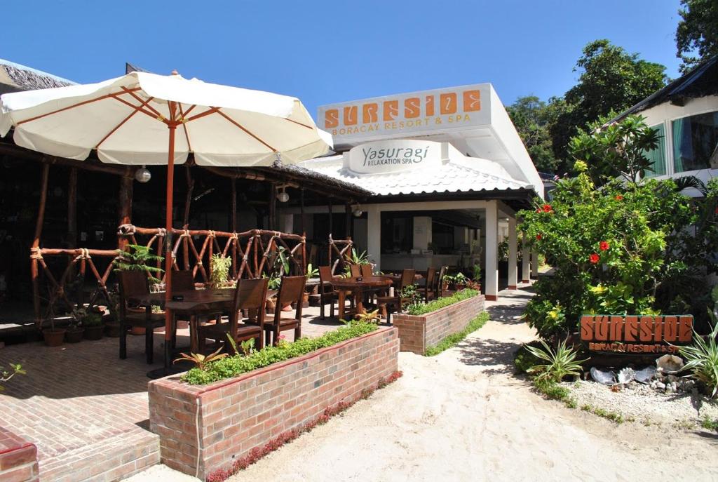 a restaurant with tables and chairs and an umbrella at Surfside Boracay Resort in Boracay