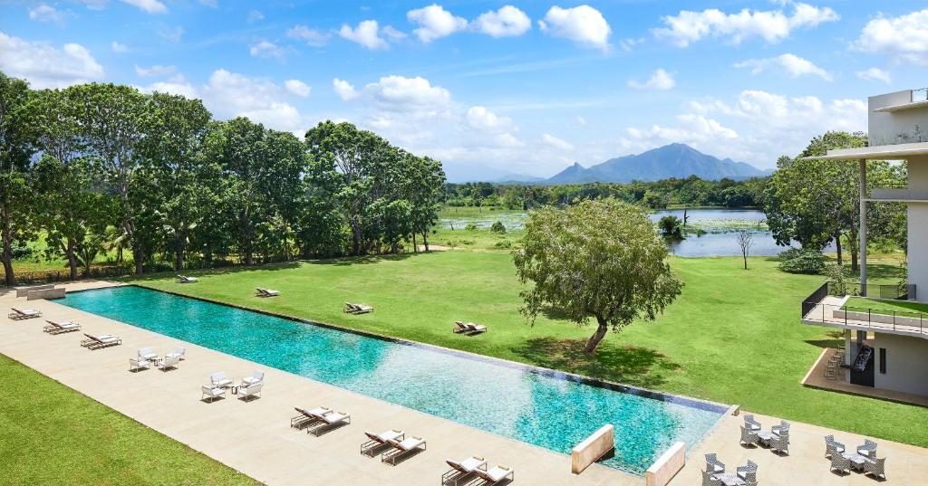 einen Blick über einen Pool mit Stühlen und Bäumen in der Unterkunft Jetwing Lake in Dambulla