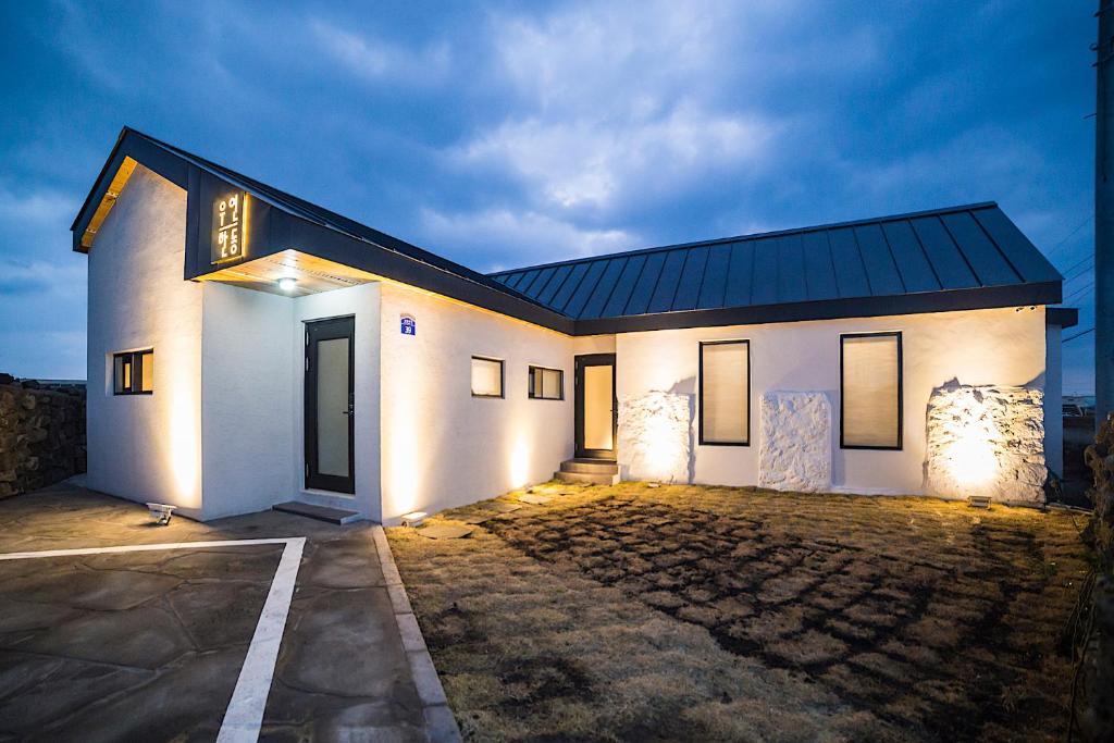 una casa blanca con techo oscuro en Wooyeon Handong Private Pension en Jeju