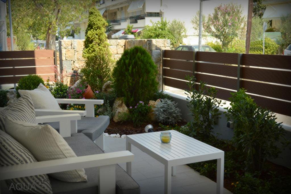 um pátio com bancos, uma mesa e plantas em Aqua Luxury Villas em Nea Poteidaia