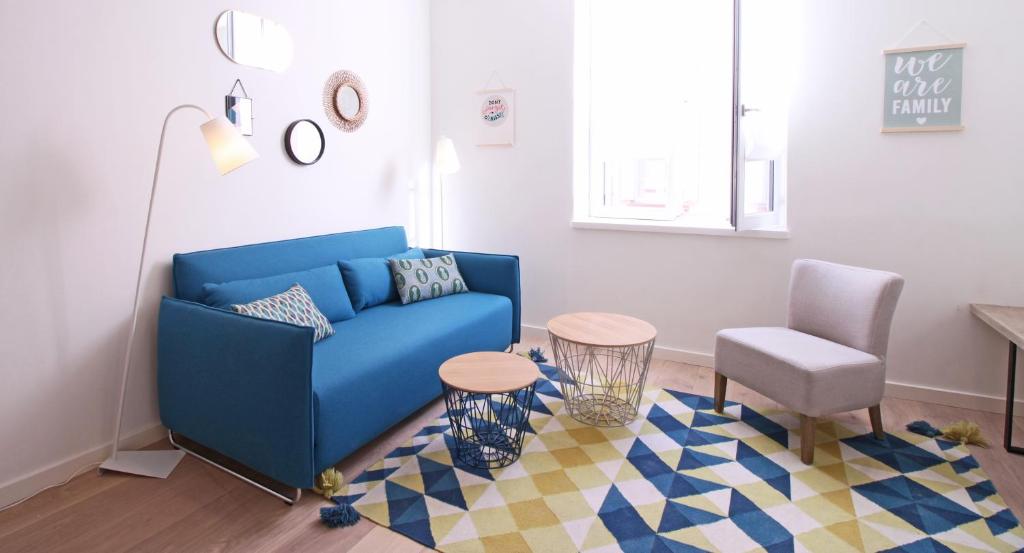 ein Wohnzimmer mit einem blauen Sofa und einem Stuhl in der Unterkunft Appartements Dom Vaissette in Toulouse