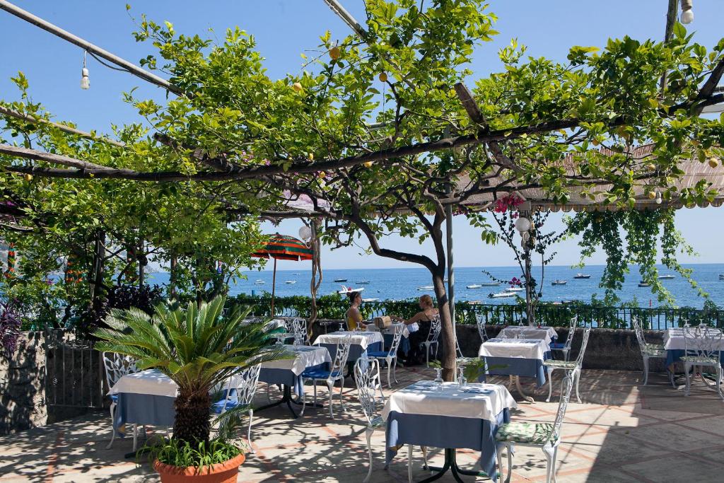 a restaurant with white tables and chairs and the ocean at Hotel Pupetto in Positano