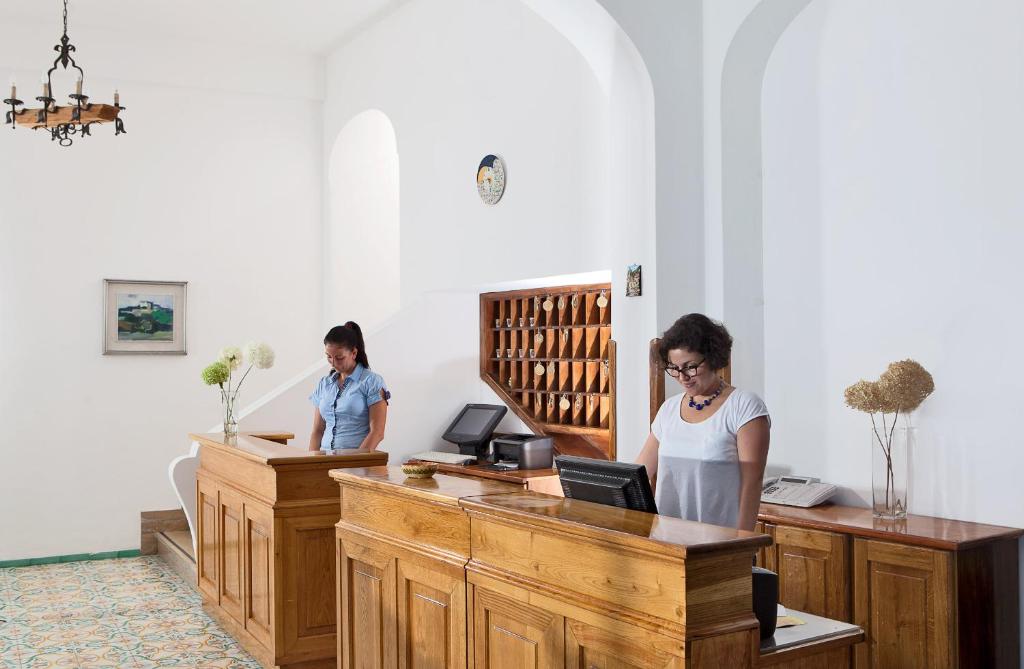 two women standing at a desk in a room at Hotel Pupetto in Positano